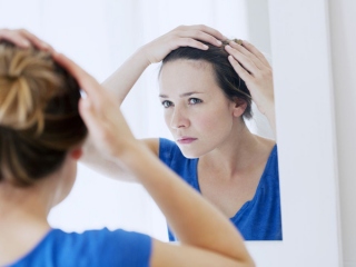 鏡で髪を見る女性