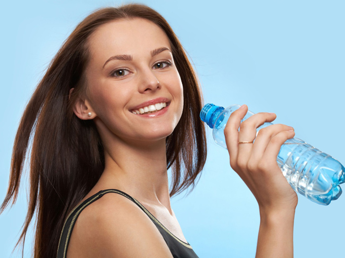水のペットボトルを片手に笑顔の女性
