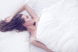 ベッドの上で女性が横になって寝ている画像