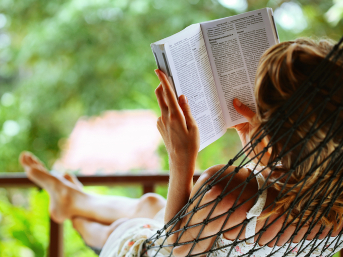 ハンモックの上で読書をする女性の画像