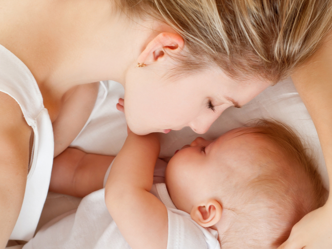 赤ちゃんといっしょに寝ている女性の画像