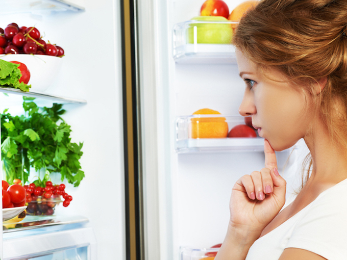 冷蔵庫の中を見て考えている女性