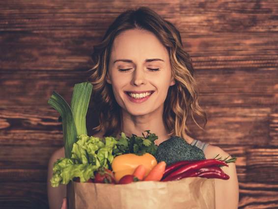 野菜の入った袋を抱えた笑顔の女性