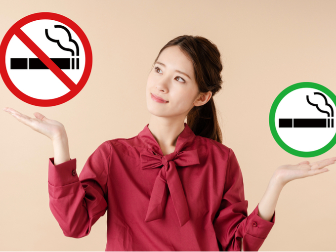 禁煙マークを見つめる女性の画像
