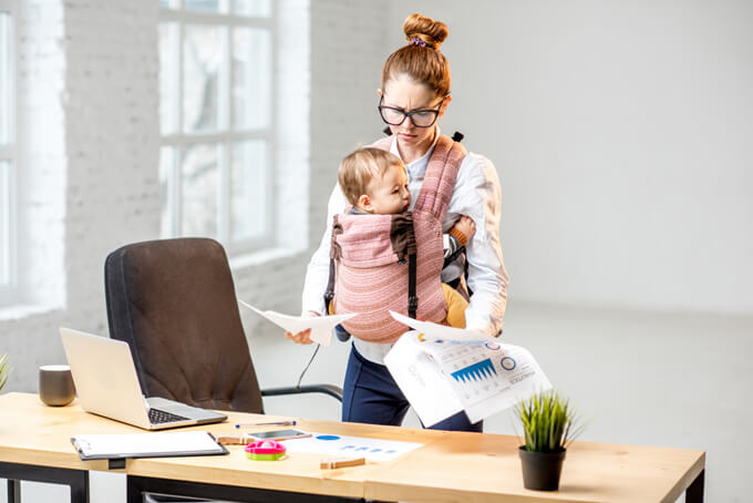 赤ちゃんを抱きながら仕事の資料を見ている女性