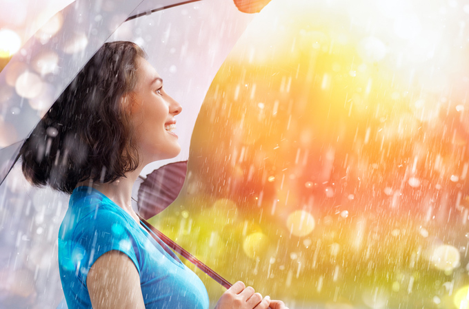 雨の中、傘をさし笑顔の女性
