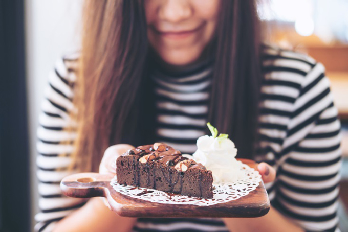 チョコレートケーキと生クリームを食べる女性