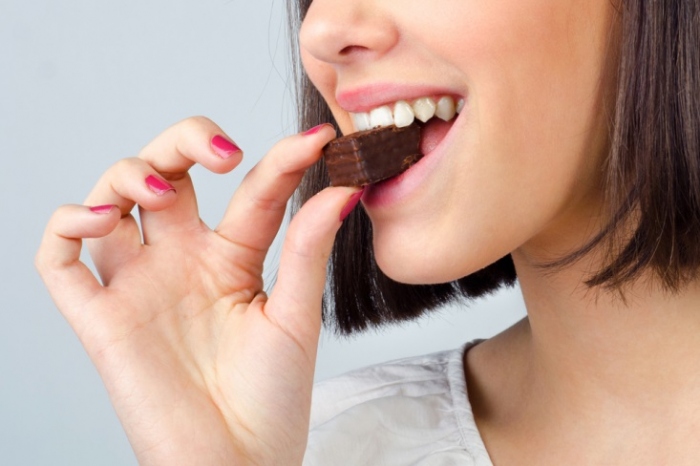 チョコレートをひと口つまむ女性