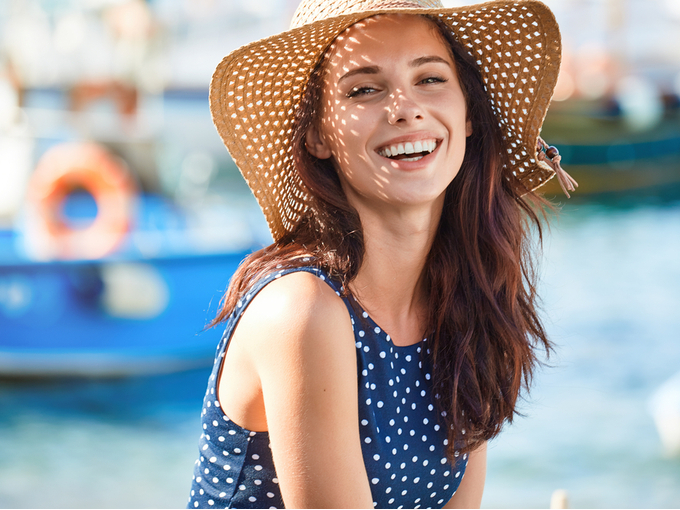 海辺で麦わら帽子をかぶった笑顔の女性