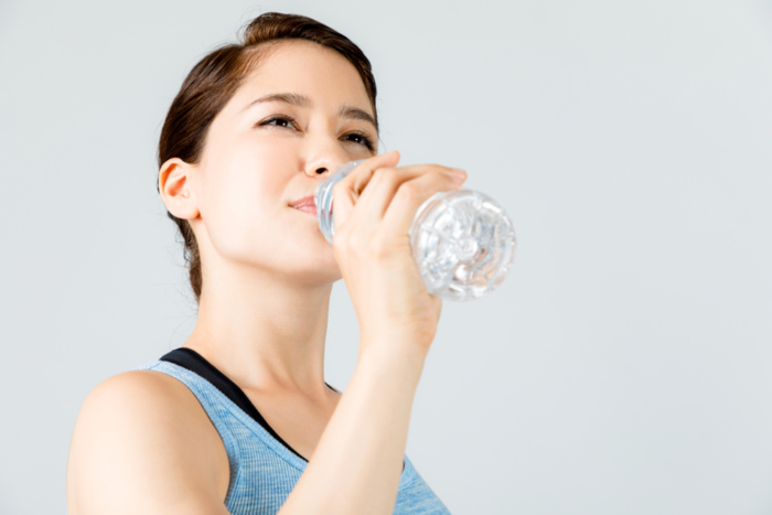 ペットボトルに入った水を飲んでいる女性の画像