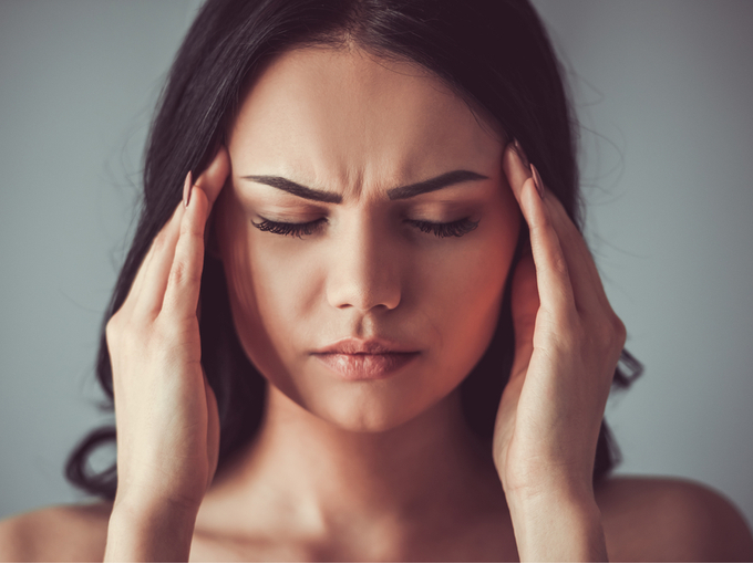 頭を押さえつらい頭痛に苦しむ女性