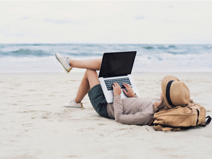 浜辺でくつろぎながらパソコンで仕事する女性