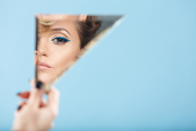 手鏡で顔をチェックする女性の画像