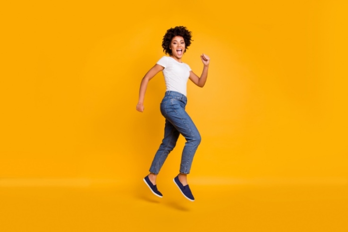 オレンジの背景で跳んでいる女性の画像