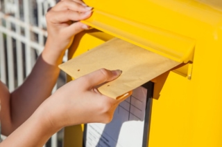 黄色いポストに手紙を入れる画像