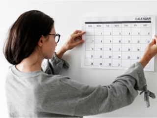 カレンダーを壁に貼る女性