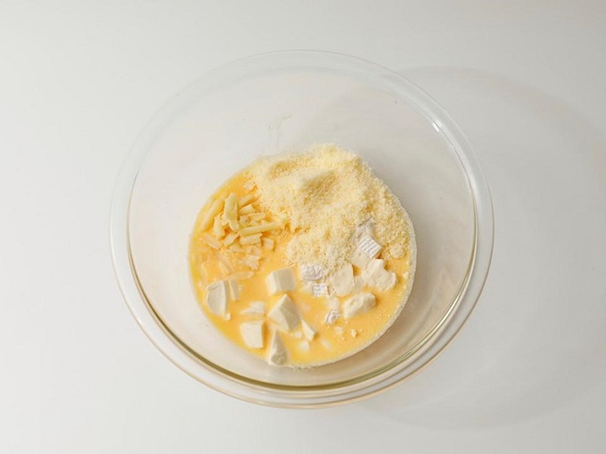 （３）（２）に（１）とシュレッドチーズ、パルメザンチーズを加え混ぜ、生地に流し入れて180℃のオーブンで25分（生地を焼いていない場合は35分）焼く。