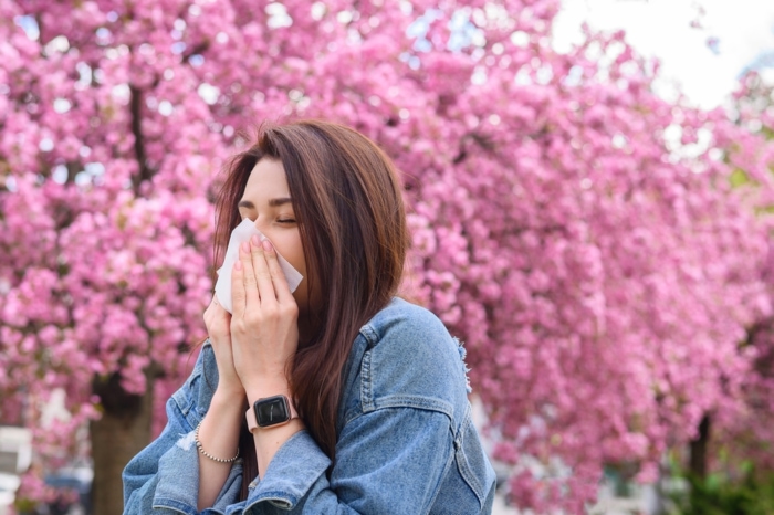 お花見シーズン、花粉症で鼻をかむ女性