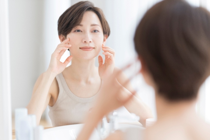 鏡をみながら肌にふれている女性