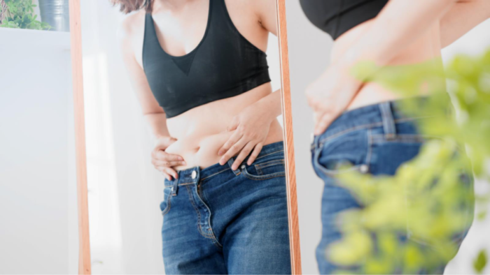 お腹の脂肪を気にする女性のイメージ