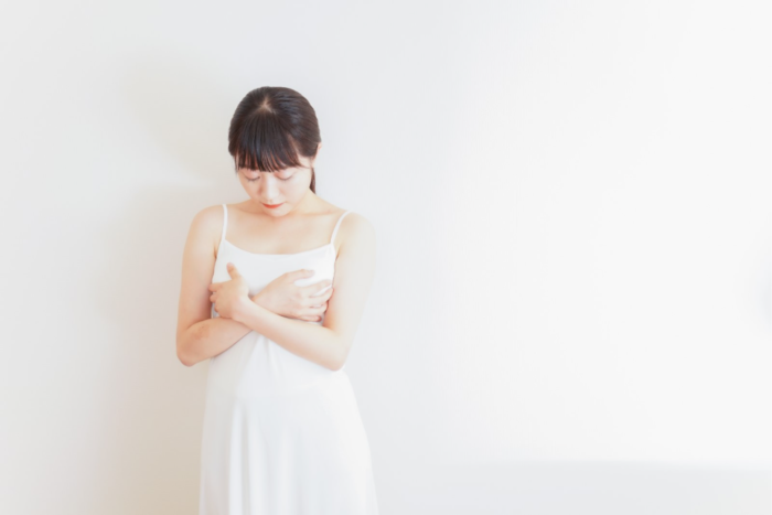 両胸を抱えるようにふれる女性のイメージ