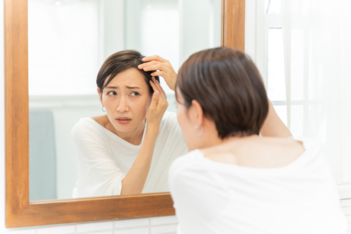 白髪を見つけた鏡を見る女性
