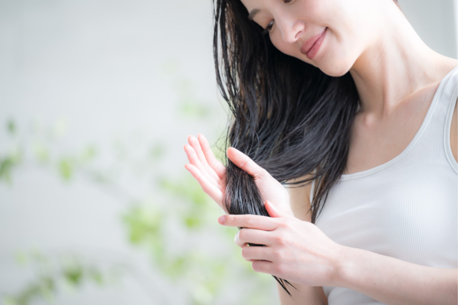 ドライヤー前にヘアオイルをつける女性のイメージ