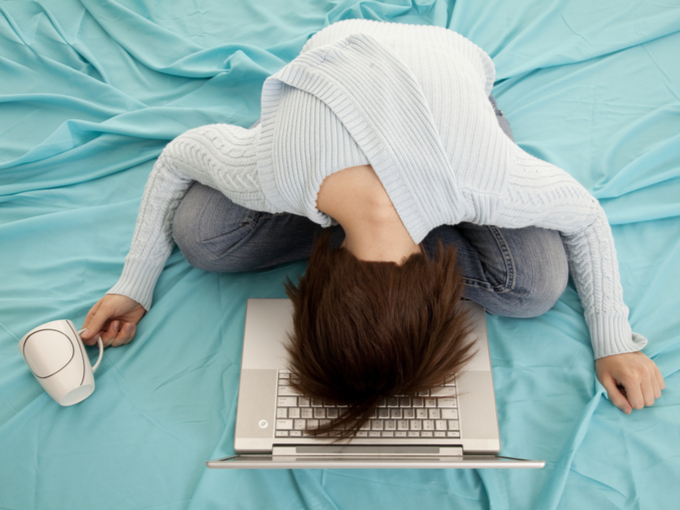 疲れてパソコンに顔をうずめて寝ている女性