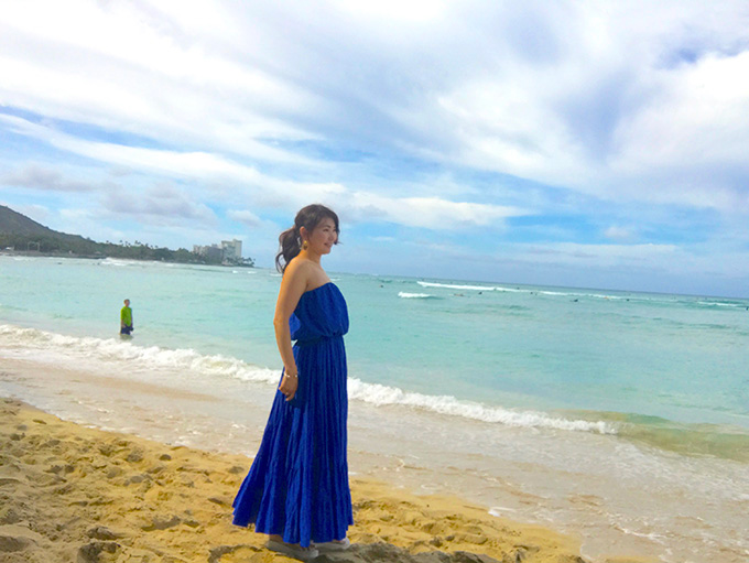 ハワイの海で木下先生がブルーのワンピースを着て立っている