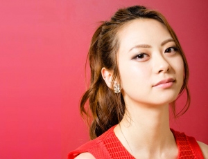 赤い壁の前に立つ山下リオさん