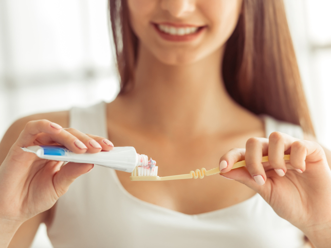 歯ブラシに歯みがき粉をつける女性