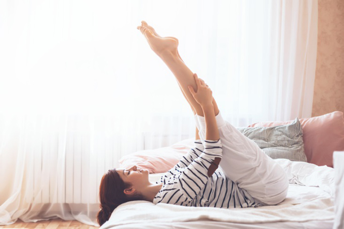 ベッドの上で脚を上げる女性