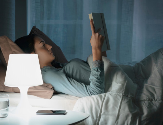 夜寝る前にベッドで本を読む女性