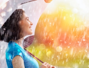 雨の中、傘をさし笑顔の女性