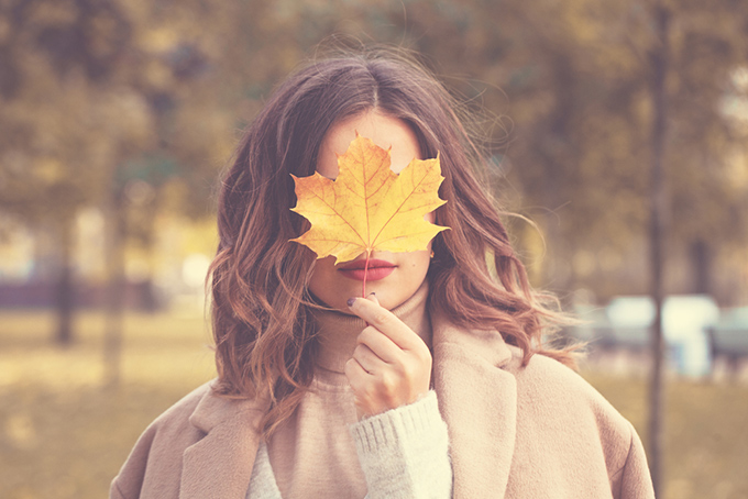 大きな葉っぱで顔を隠している女性