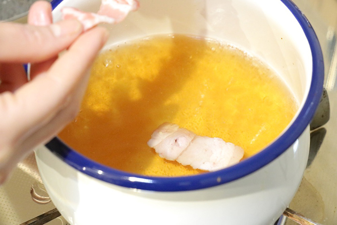 小鍋にスープを入れて豚肉を入れている画像