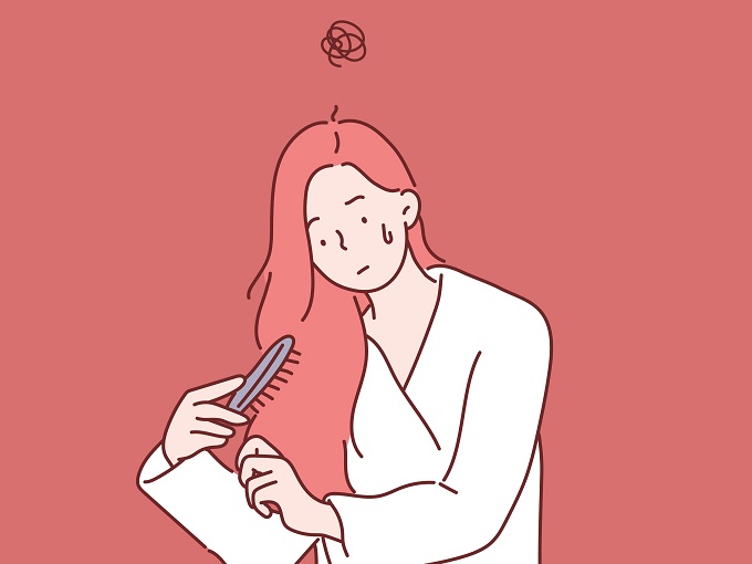 髪をブラシでとかしている女性